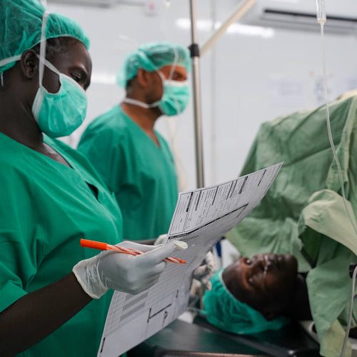 Medical professionals in green scrubs and masks in a hospital setting.