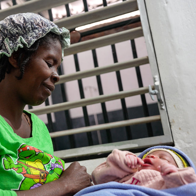 Woman in a green shirt holding a baby in a hospital setting