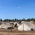 Row of tents set up in a field with a clear blue sky.